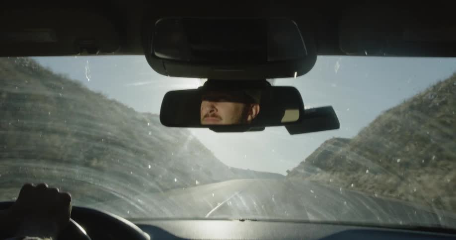 Man washes his windshield while driving