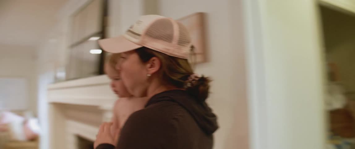 A woman carries a baby through the hallway