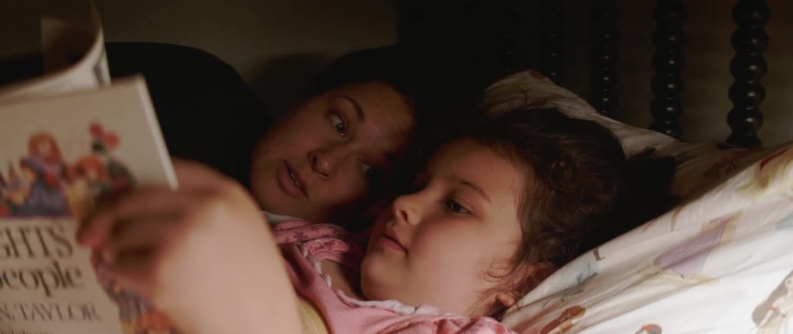 A woman and young daughter read a book together