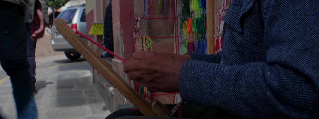 Person braids red string together outside during the day