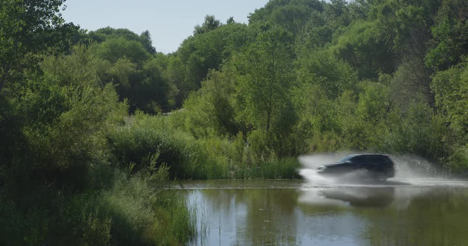 Car drives and splashes in water