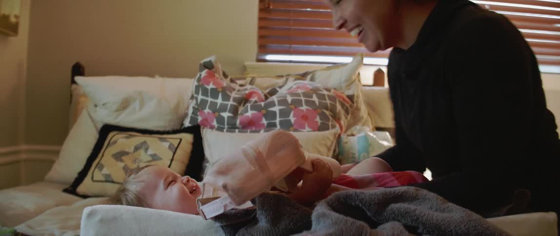 Woman plays with a baby on a bed