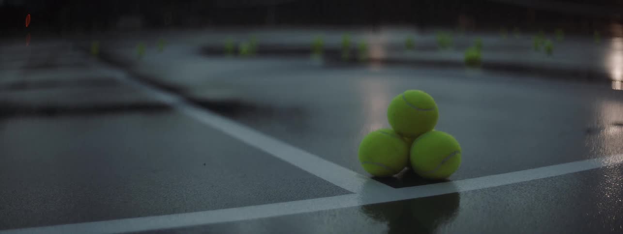 Three tennis balls are stacked on each other on the tennis court