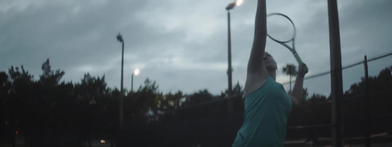 A woman serves a tennis ball