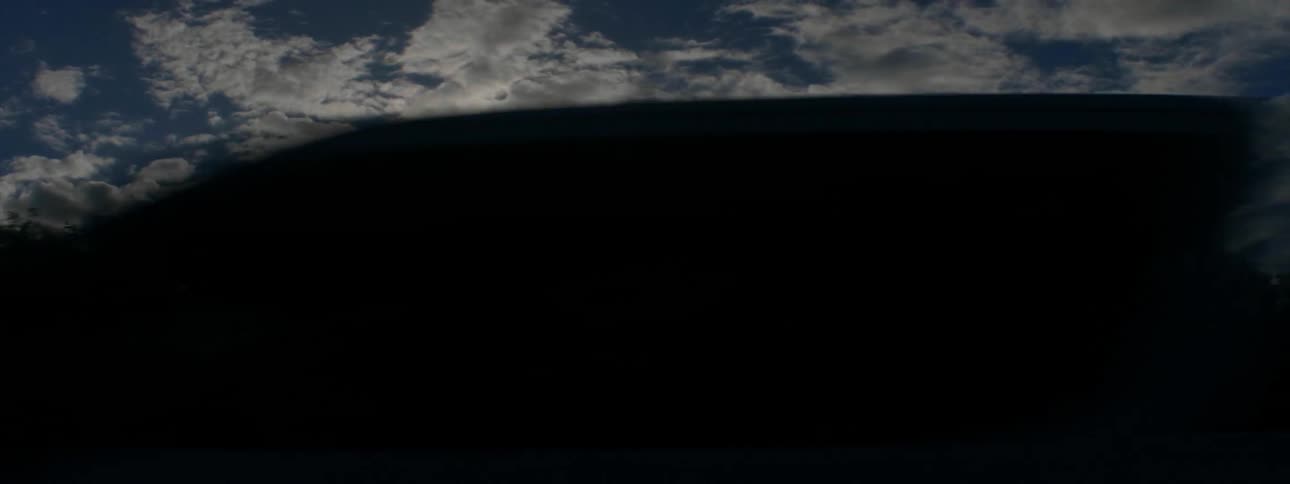 The sun shines through sparse white clouds