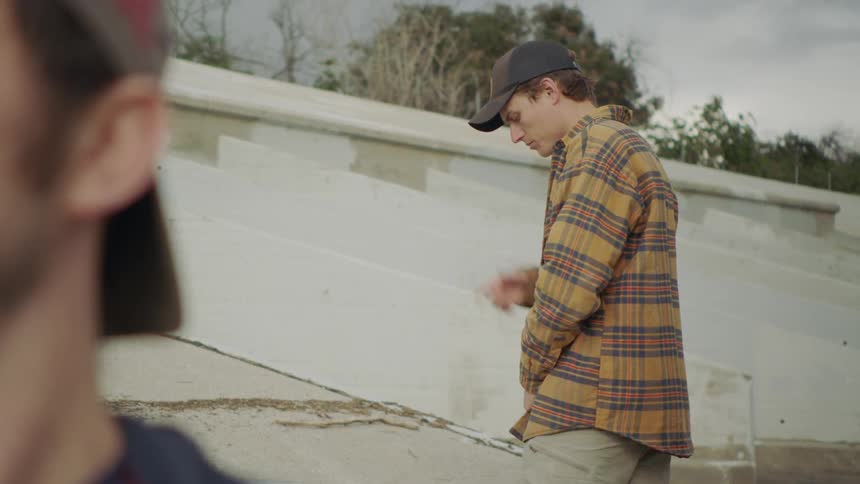 Man pees outside while smoking a cigarette