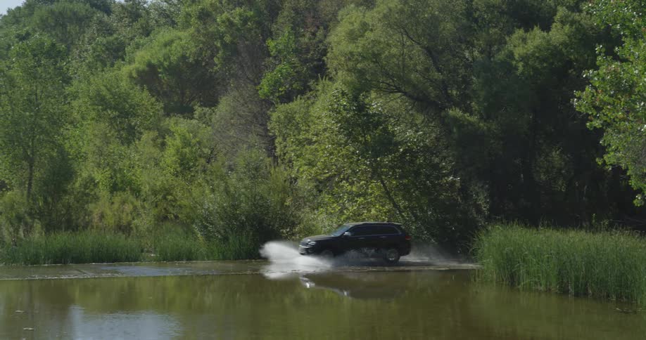 The vehicle races through the shallow water