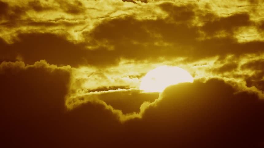 The sun is setting behind the clouds