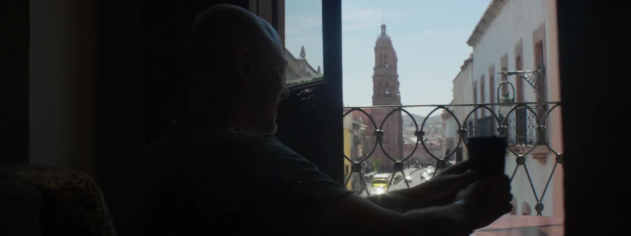 A man is served a cup of coffee on a balcony
