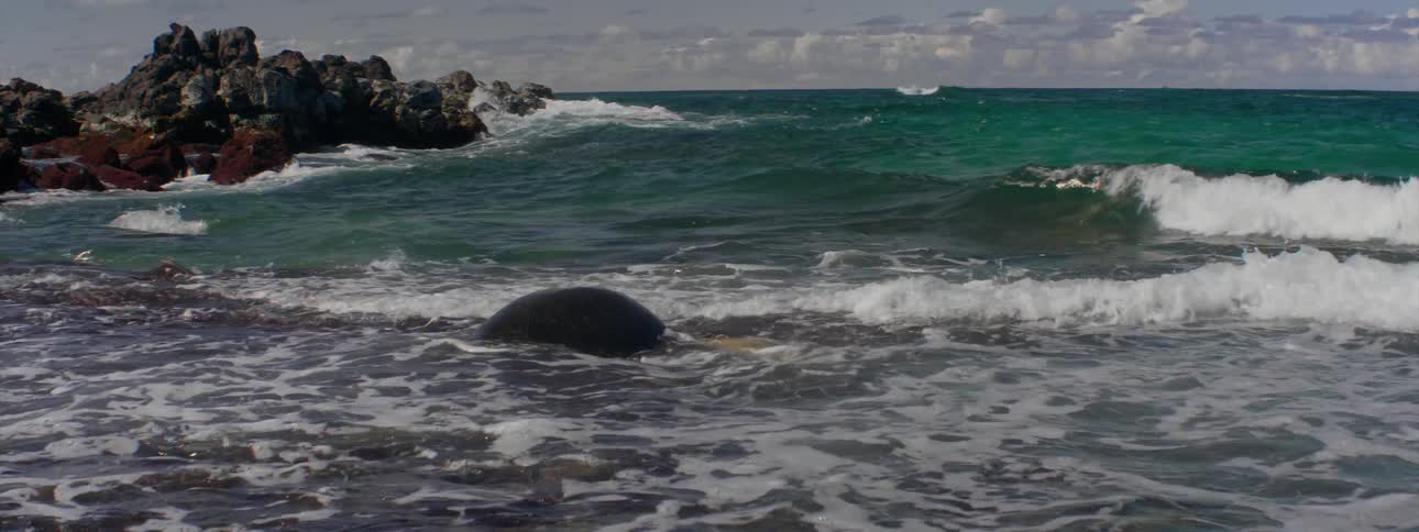 The tide flows towards the rocky shore