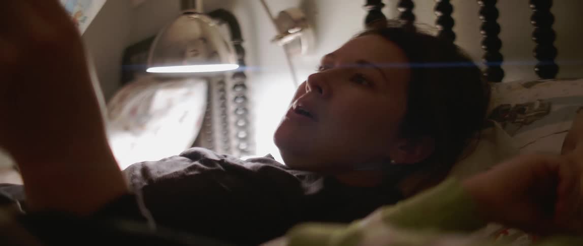 Woman reads a book to a child in bed