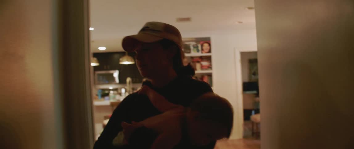 A woman carries a young child through the house
