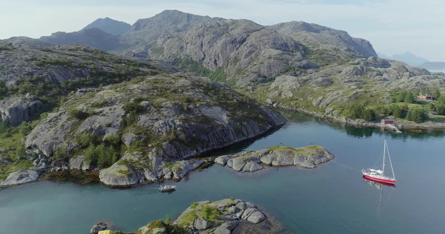 The boat is sailing towards the large rocks near the shore