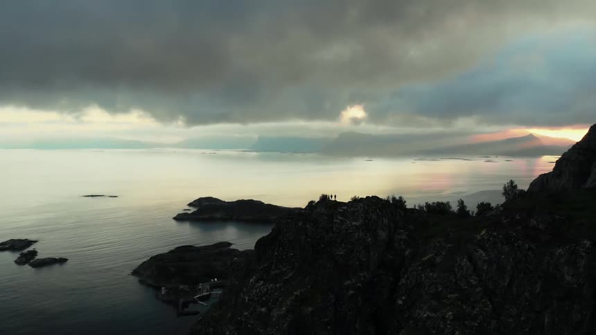 Hikers stand on a coastal cliff at sunset