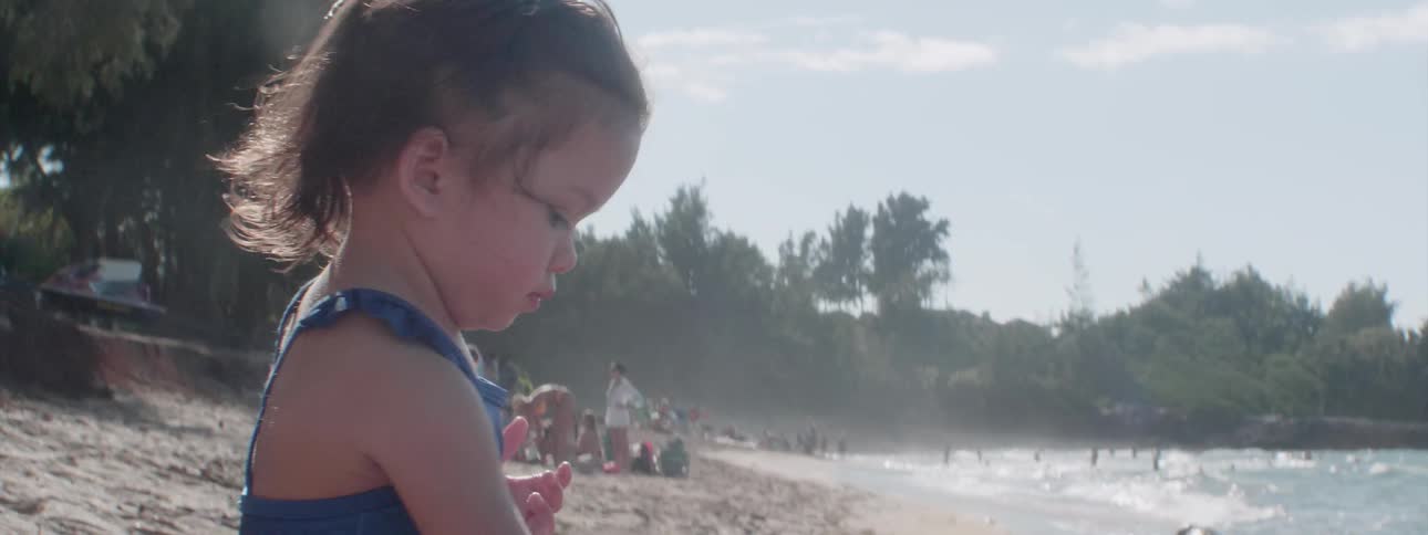 A young girl plays in the sand on the beach