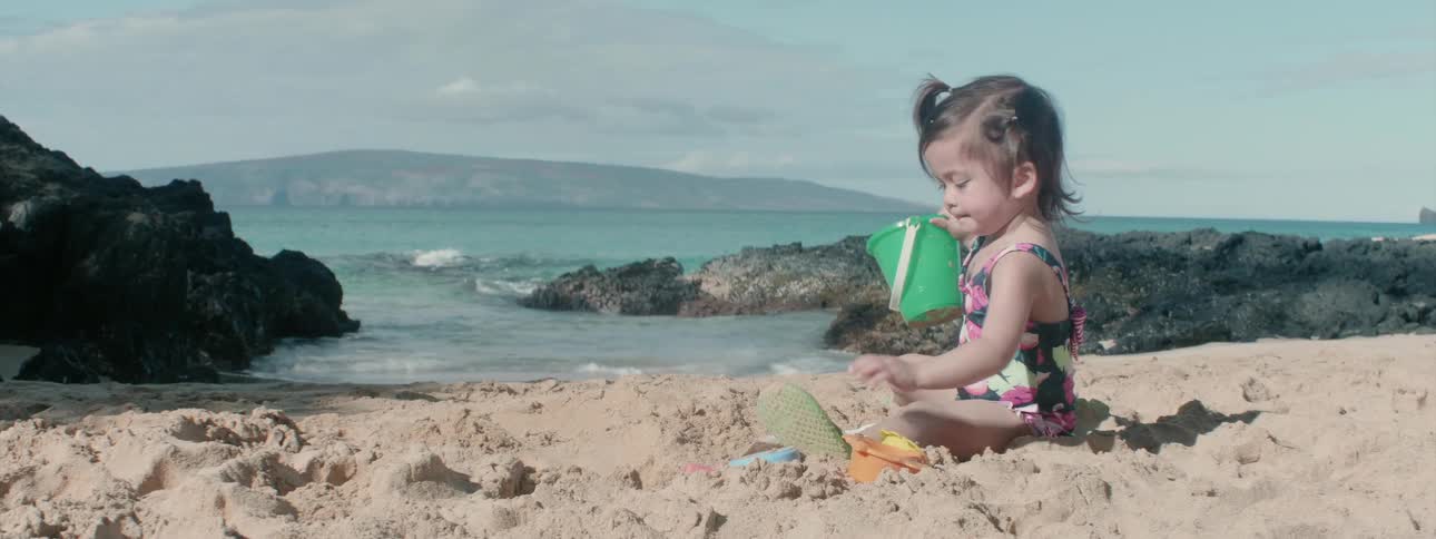 A child is digging in the sand on the beach