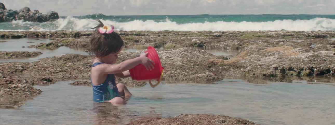 A girl plays with a pail on a beach
