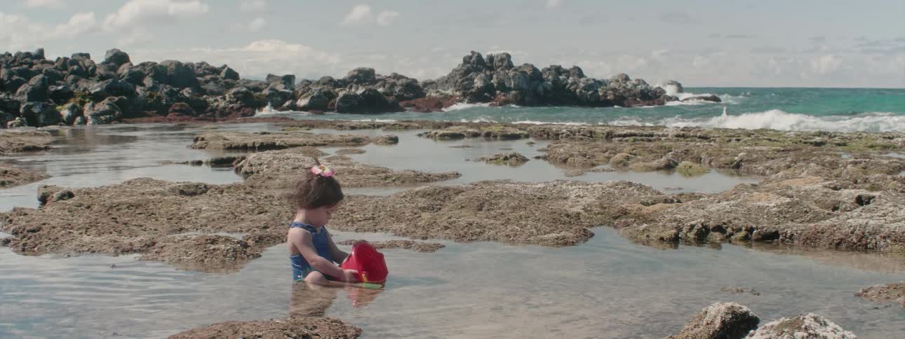 A young girl plays in the sand on the beach