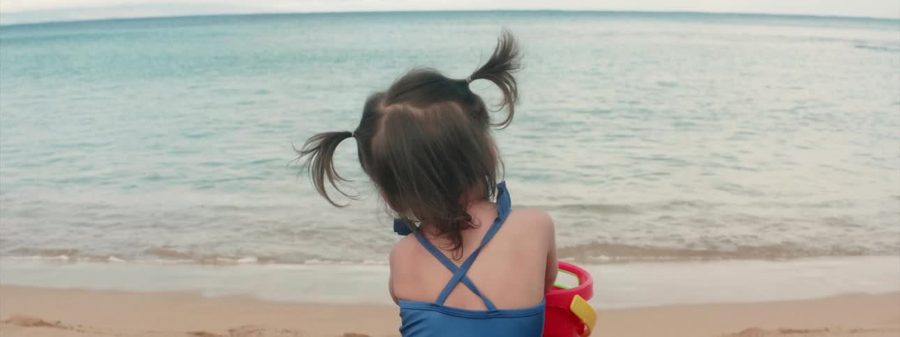A child is playing with a pale on the beach