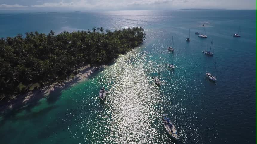 Overhead view over boats in the ocean next to a sandy beach
