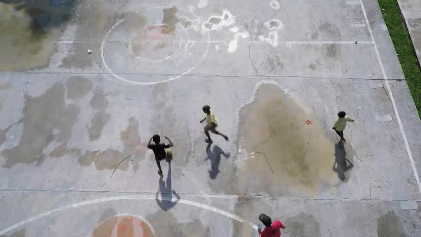 Boys kick a ball on a concrete court
