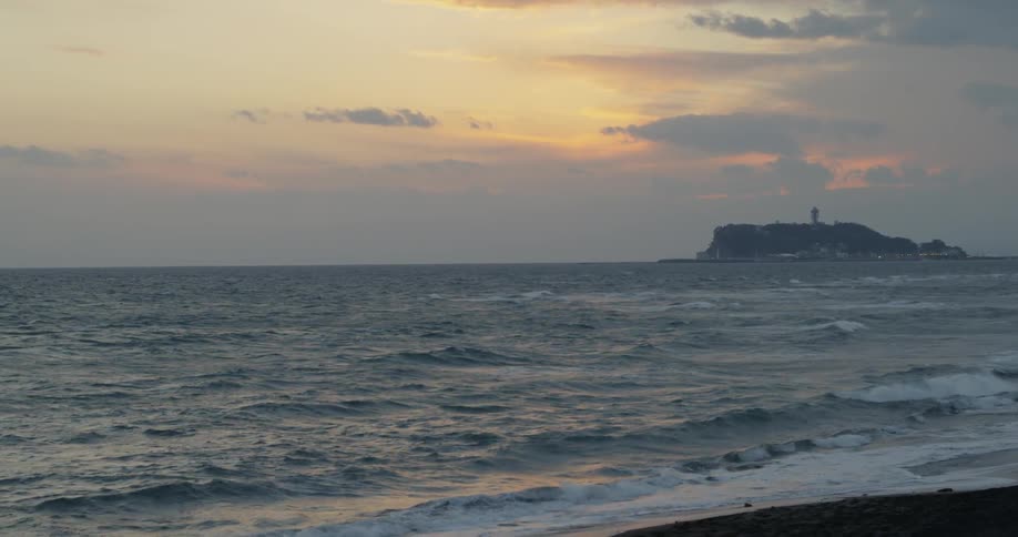 Waves are rolling onto a beach at sunset
