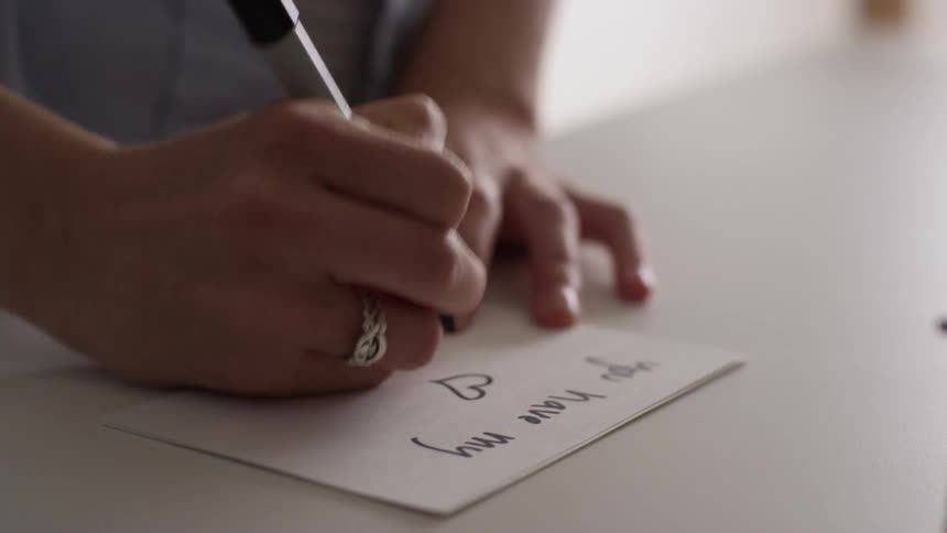 A woman writes on a notecard with a black marker
