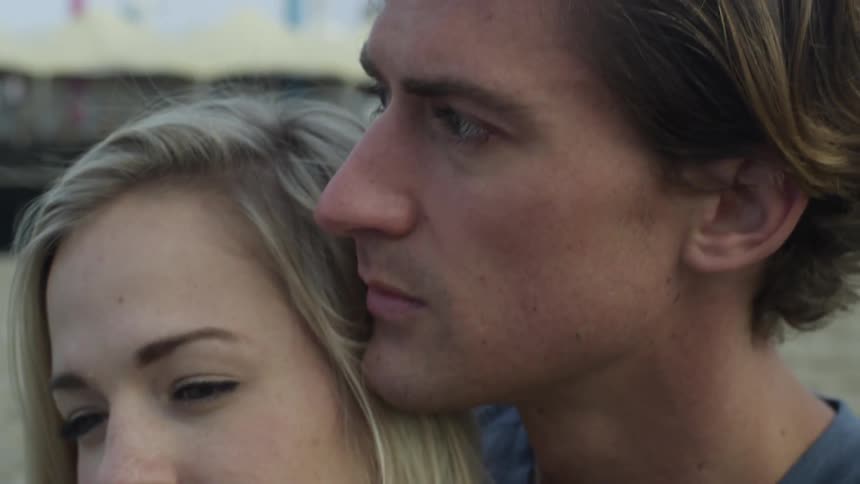A man and woman cuddle on the beach