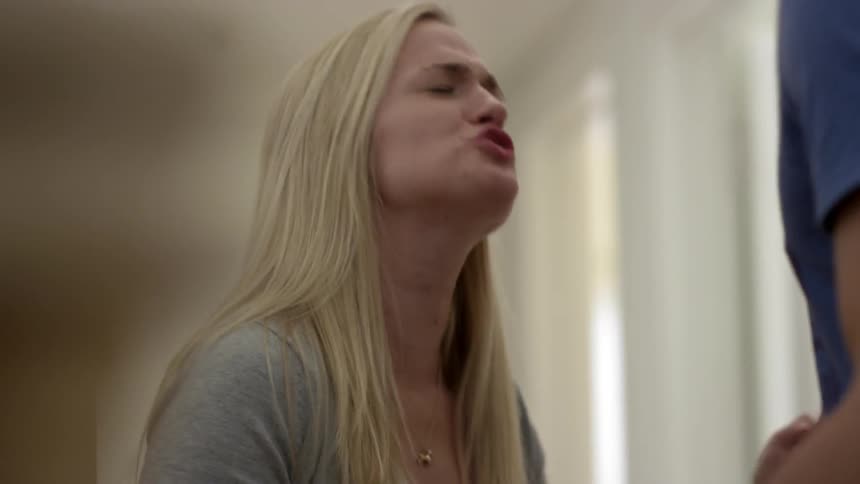 A young woman with blonde hair angrily yelling at a man who is much taller than her and pushing him