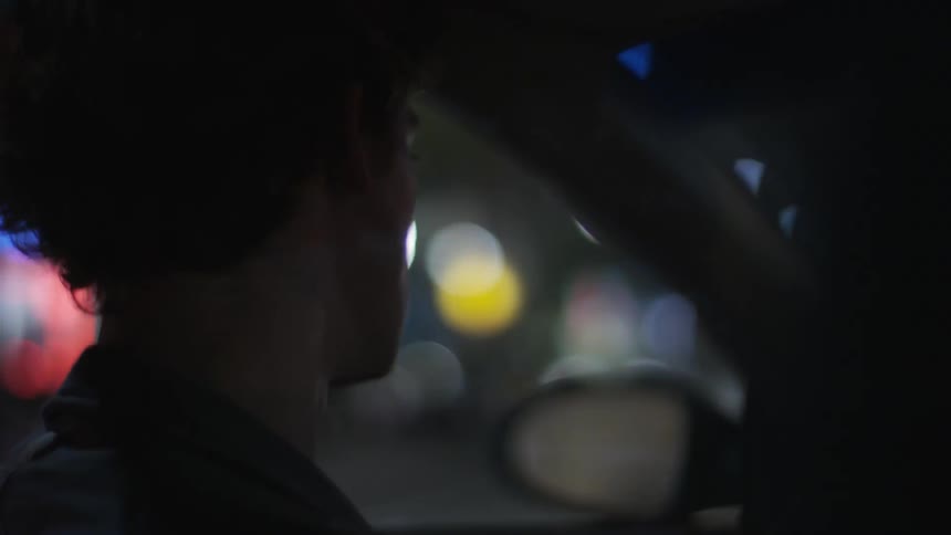 Man driving a car down a street at night