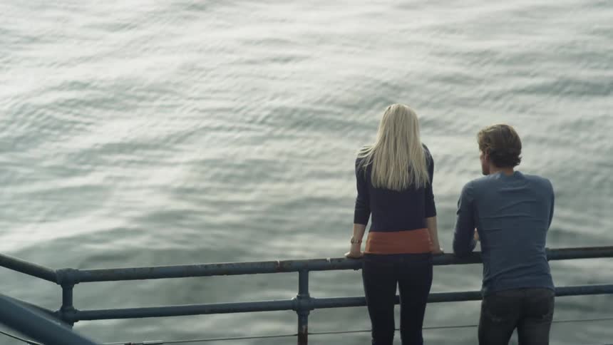 A man and woman overlook rippling water