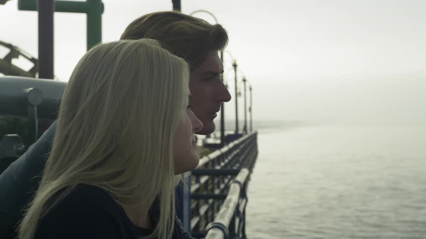 Man and woman stand by a railing on the water