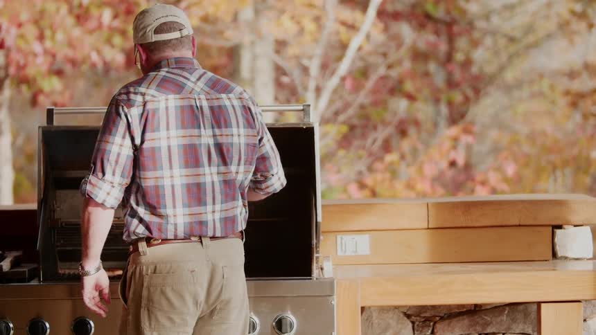 A man stands at a grill cooking food