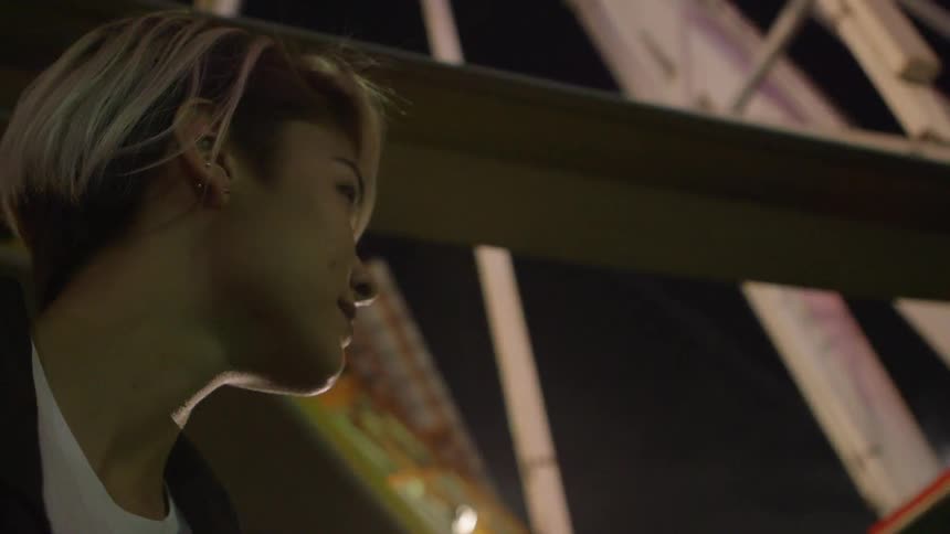 Amusement park rides and colorful lights behind a woman standing in profile