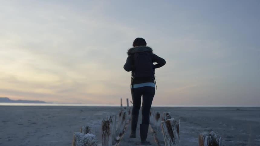 Woman walks on a beach at sunset