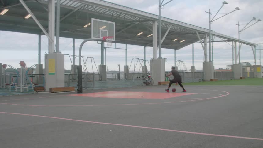 Man shoots hoops on a basketball court by himself