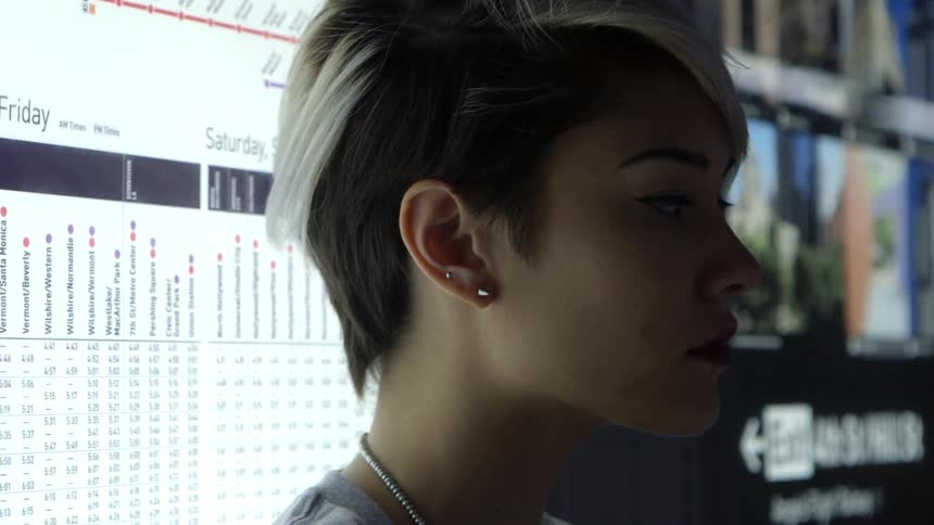 A young woman standing in front of a large sign looking around