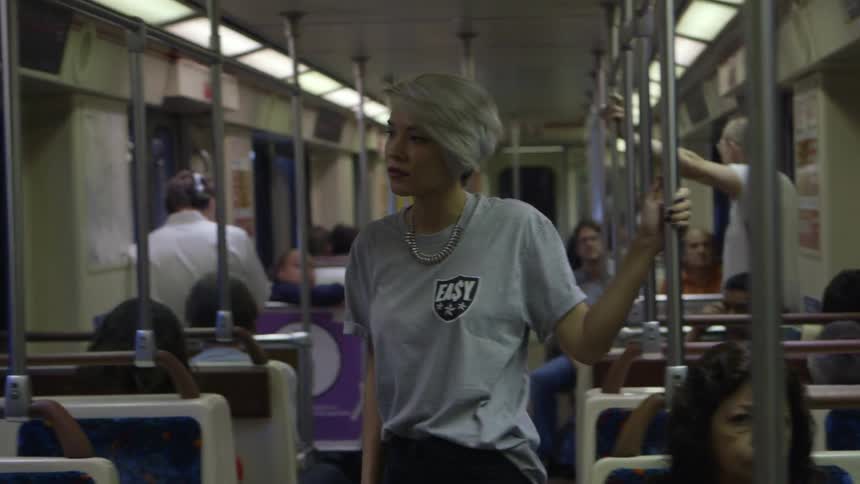 A woman with white hair stands up on a bus