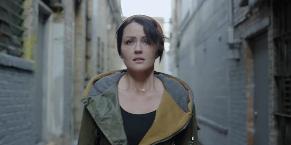 A woman looks frightened walking down a narrow alley