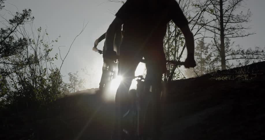 Two people are riding mountain bikes down a hill