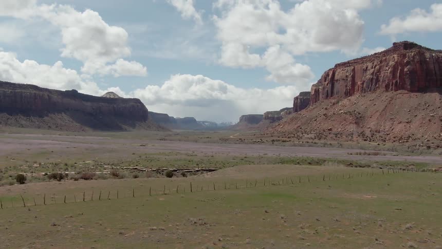 A grassy patch of land surrounded by two large red rock mountains