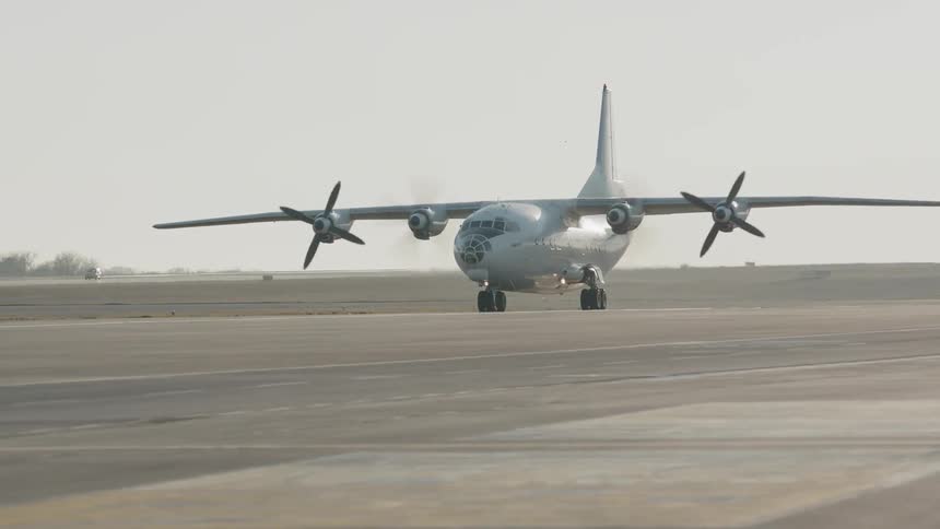 A large plane with propellers moves down a runway