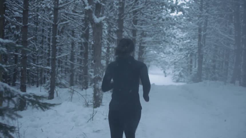 Woman jogs in a snowy forest
