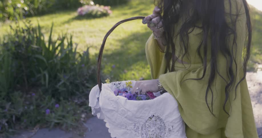 Woman holding a basket and touching the flowers in it