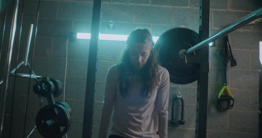 Woman stands and looks down in a gym
