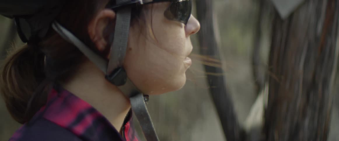 A woman wearing a helmet is standing in the forest