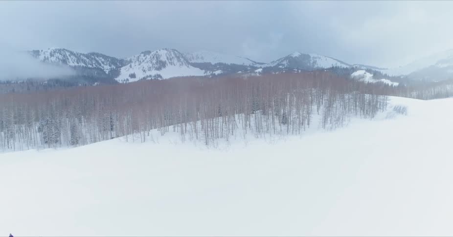 Snowy grassy terrain near mountains on a cloudy day
