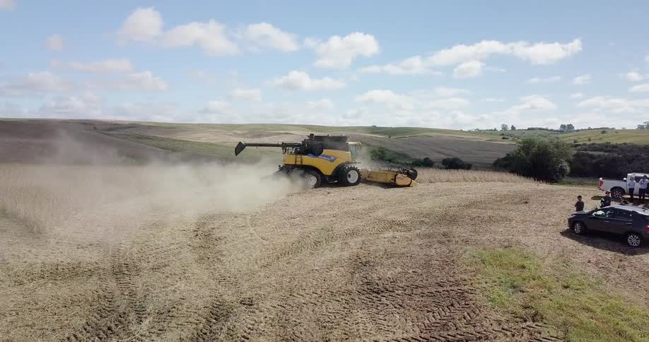 Farm equipment kicks up dust as it clears a field
