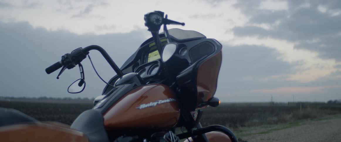 A motorcycle is parked on the side of a dirt road