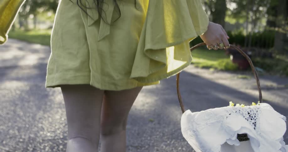 Woman carries flowers in basket as she walks along a road